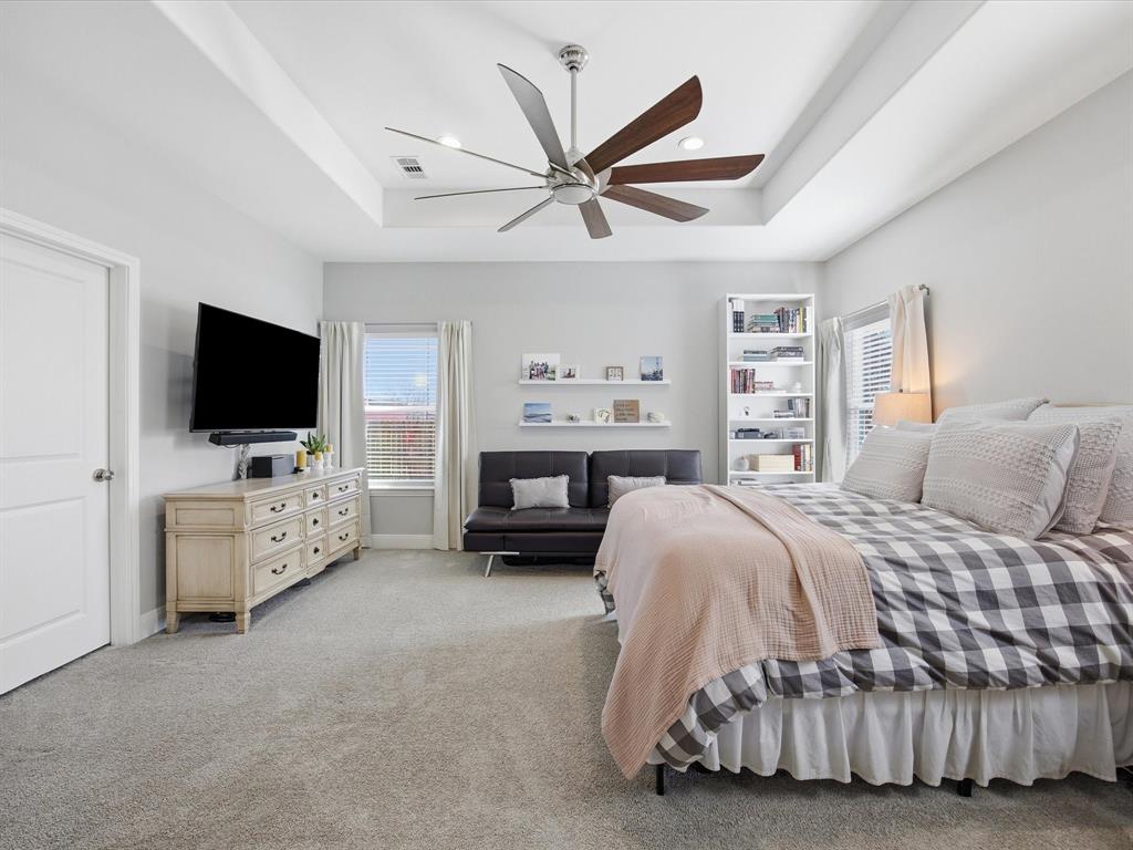 608 Timberline Drive Bridgeport, TX 76426 - Photo 15 of 33 Light-filled primary bedroom with tray ceiling, modern fan, plush carpet, and built-in shelving.