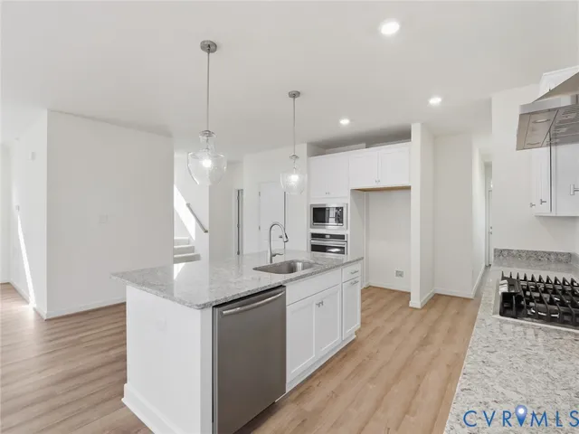 a kitchen with stainless steel appliances kitchen island granite countertop a sink a refrigerator and a stove