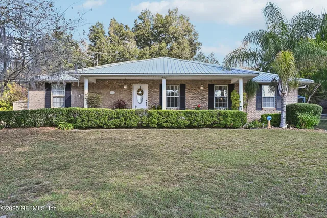 a front view of a house with yard and trees