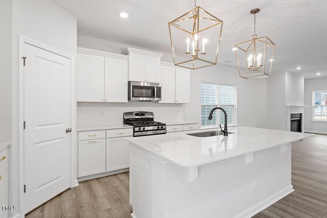 a kitchen with stainless steel appliances granite countertop a sink a stove a refrigerator cabinets a dining table and chairs