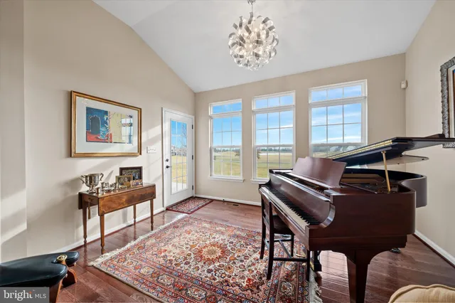 a kitchen with stainless steel appliances granite countertop a refrigerator a sink dishwasher a stove and a dining table with wooden floor