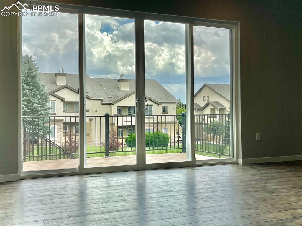 6593 Vistancia Avenue Colorado Springs, CO 80922 - Photo 6 of 21 a view of empty room with wooden floor and a floor to ceiling window