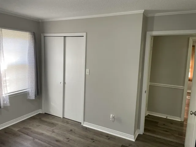 an empty room with wooden floor door and windows