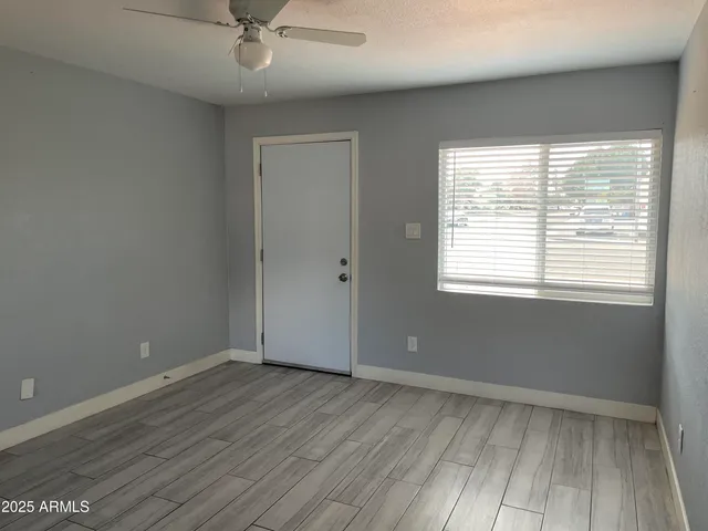 a view of an empty room with wooden floor and a window