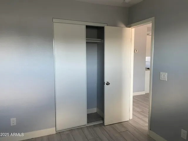 a view of an empty room with wooden floor and closet