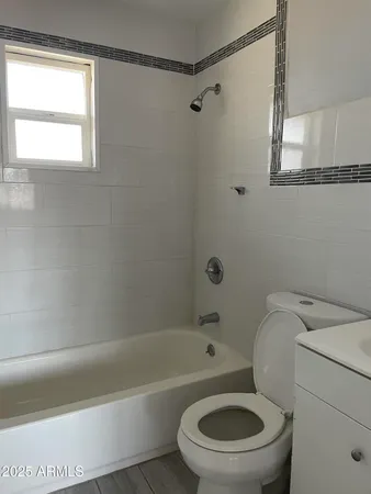 a white toilet and a bath tub sitting next to a window