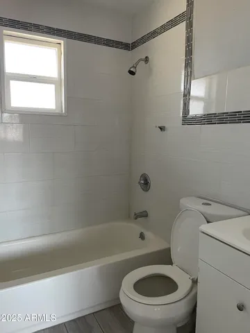 a white toilet and a bath tub sitting next to a window