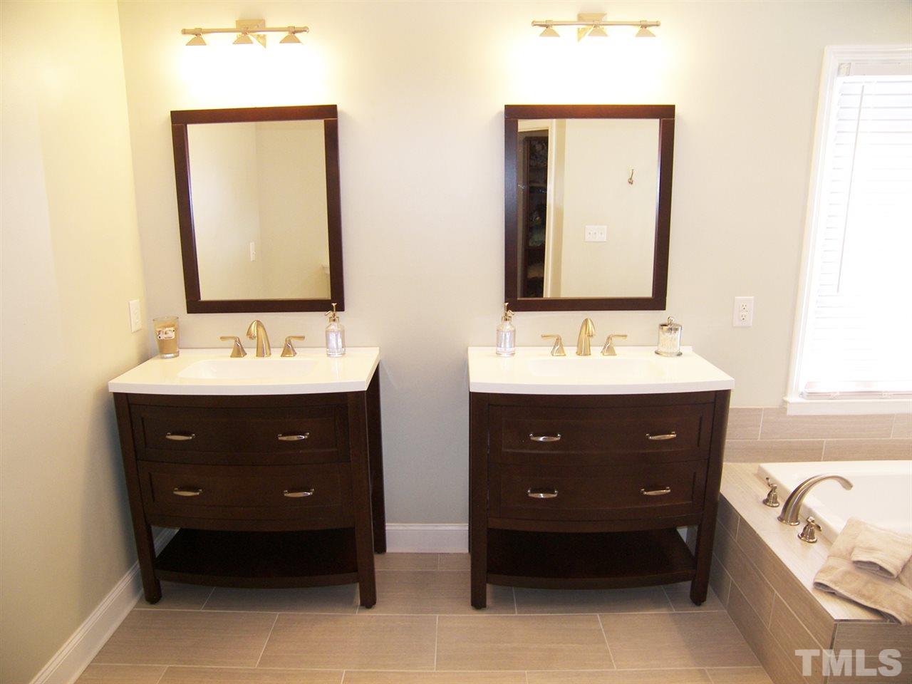 11933 Fairlie Place Raleigh, NC 27613 - Photo 14 of 25 a bathroom with a tub a double vanity sink and mirror