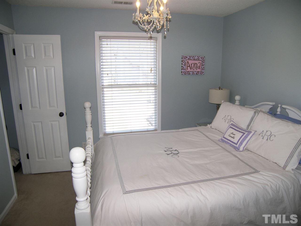 11933 Fairlie Place Raleigh, NC 27613 - Photo 16 of 25 a bedroom with a bed and a chandelier