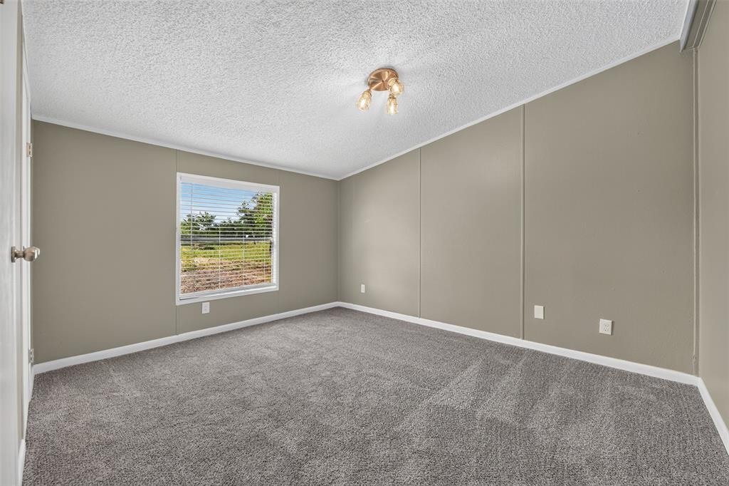 449 Big Salty Lane Springtown, TX 76082 - Photo 20 of 25 Carpeted room featuring a window with horizontal blinds, neutral wall paneling, and a ceiling-mounted light fixture