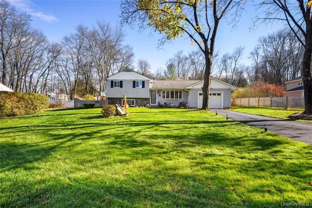 a view of a house with a big yard and large trees