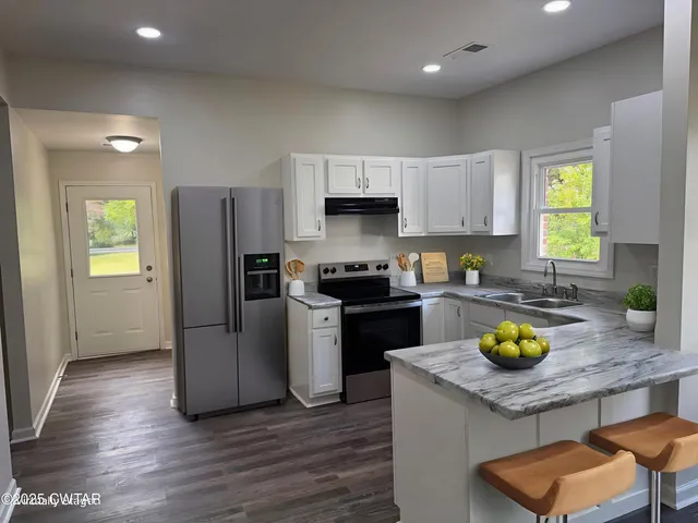 a kitchen with granite countertop a stove and a wooden floors