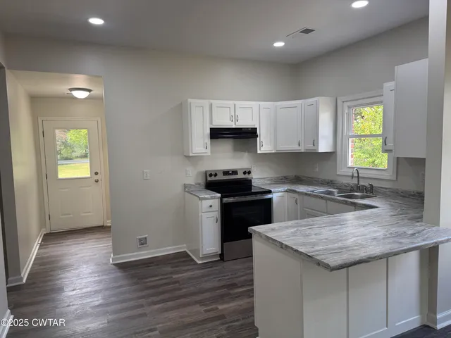 a kitchen with stainless steel appliances granite countertop wooden cabinets a refrigerator a stove a sink and a stove