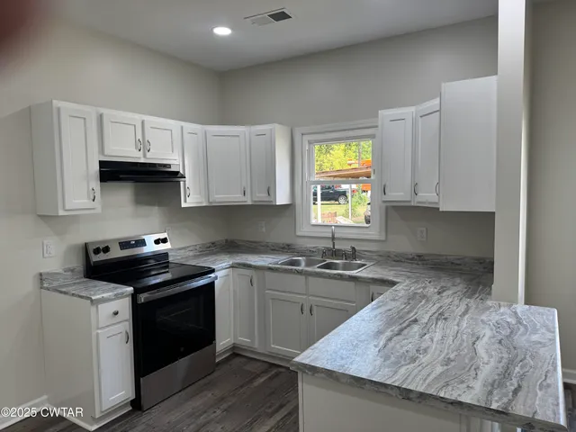 a kitchen with granite countertop a stove and a sink