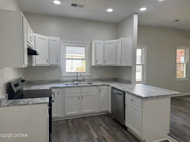 a kitchen with granite countertop a sink stove and cabinets