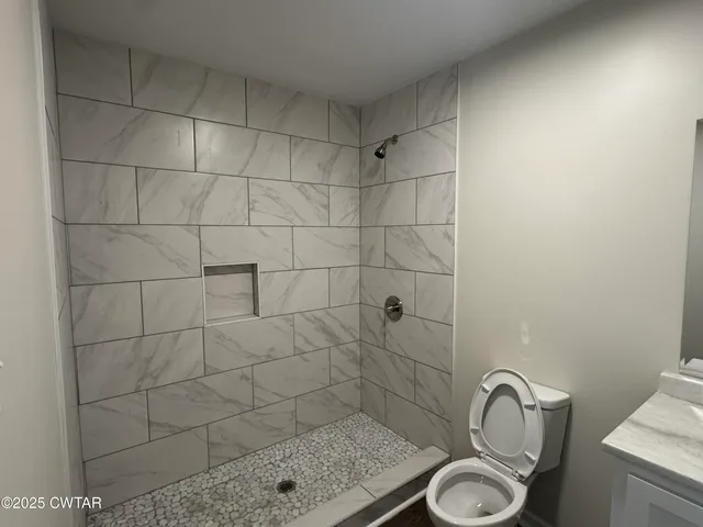 an empty room with wooden floor chandelier fan and windows