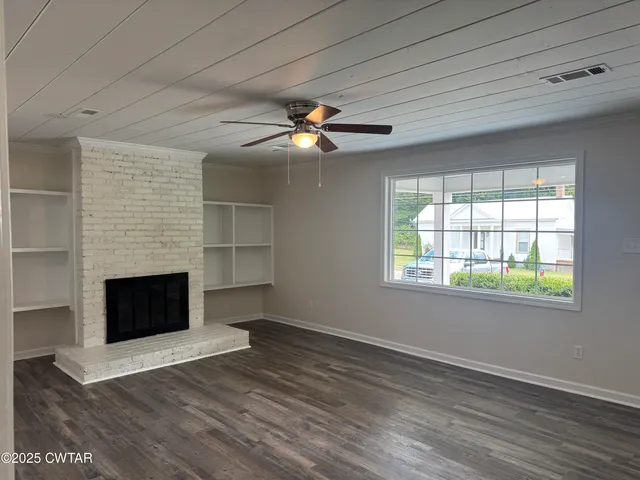 an empty room with windows and fireplace