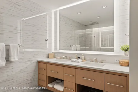 a bathroom with a sink double vanity granite tub shower and a mirror