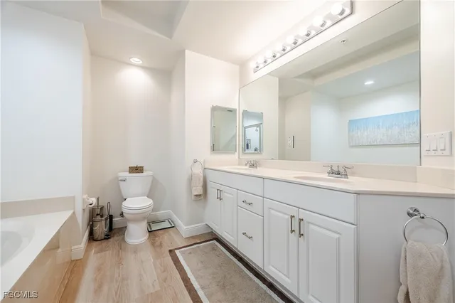 a spacious bathroom with a double vanity sink a mirror and a toilet