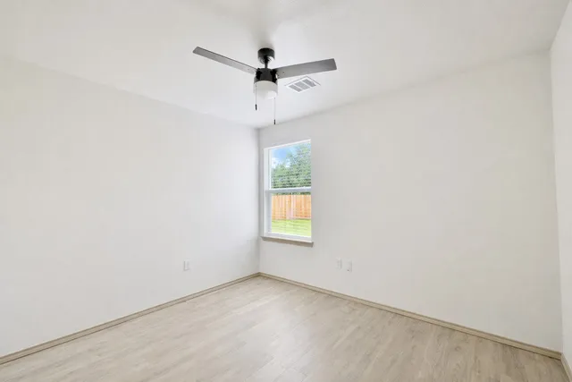 an empty room with a window and a ceiling fan
