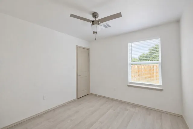 an empty room with ceiling fan and window