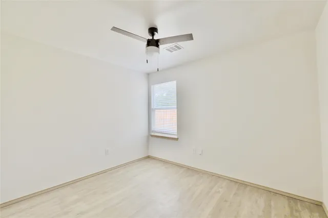 an empty room with a window and a ceiling fan