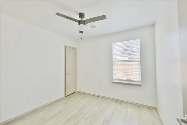 an empty room with a window and a fan