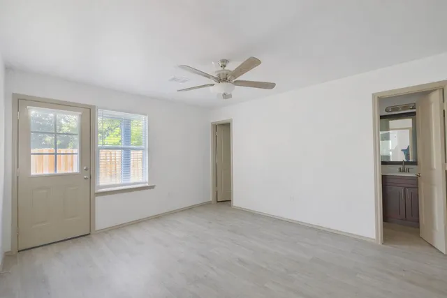 an empty room with chandelier fan and windows
