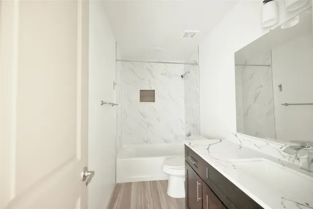 a bathroom with a bathtub shower sink vanity and toilet