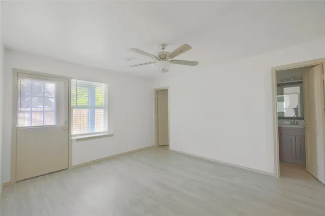 an empty room with chandelier fan and windows