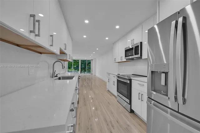 a kitchen with stainless steel appliances a refrigerator oven a sink dishwasher and a stove with wooden floor