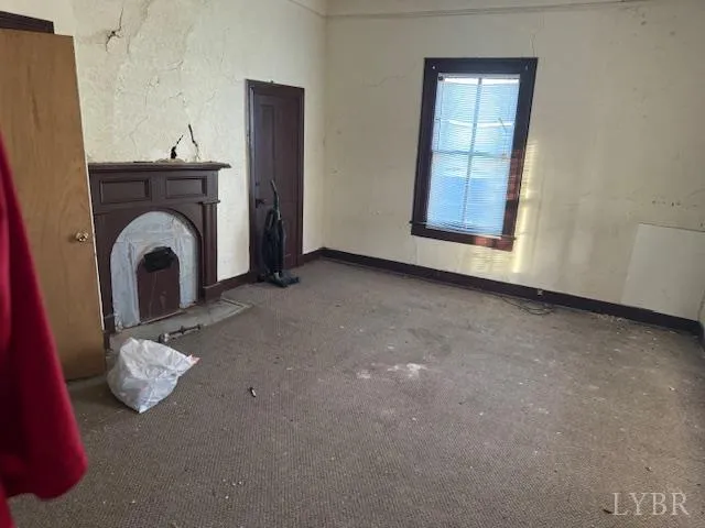 a view of an empty room with chandelier fan and a fireplace