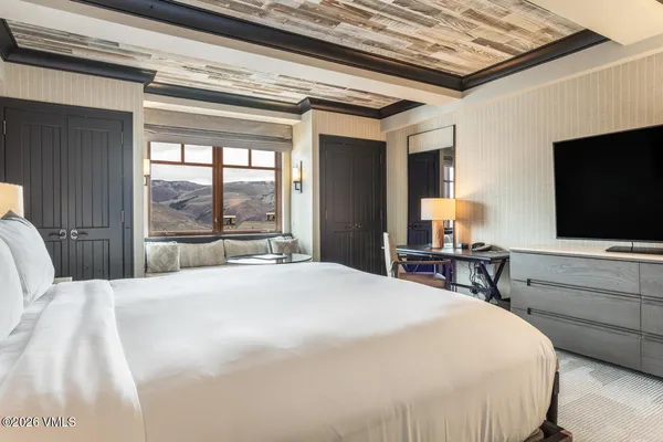 a bedroom with a bed and a flat tv screen on dresser