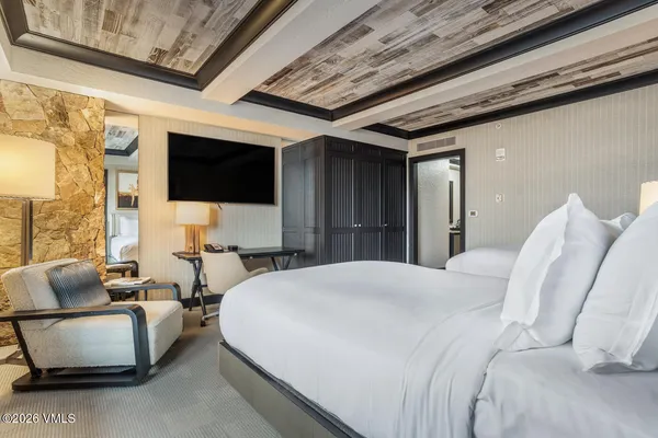a spacious bedroom with a bed and a flat screen tv