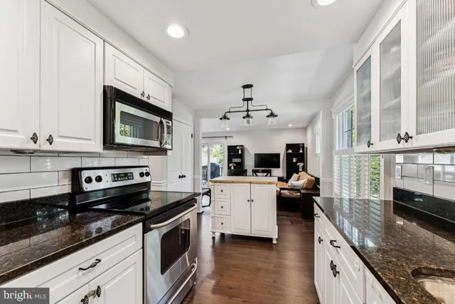 a large kitchen with stainless steel appliances granite countertop a stove and a microwave