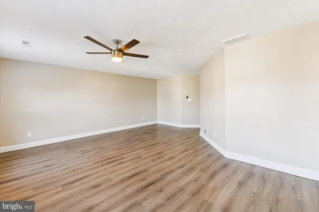 an empty room with wooden floor and a ceiling fan