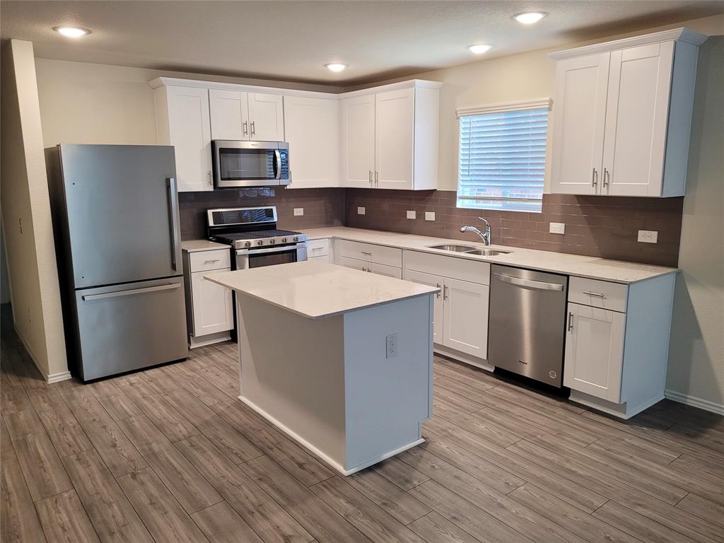 1049 Knightly Lane Haslet, TX 76052 - Photo 4 of 19 a kitchen with wooden cabinets and stainless steel appliances