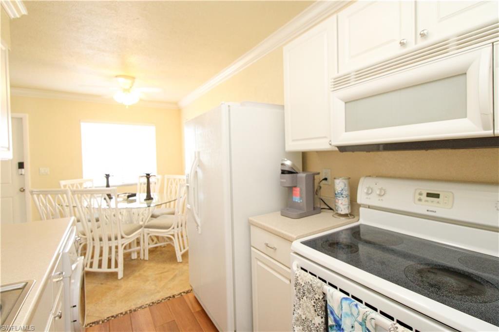 4615 Bayshore Drive, Unit E4 Naples, FL 34112 - Photo 16 of 30 a kitchen with a sink a stove and white cabinets next to a window