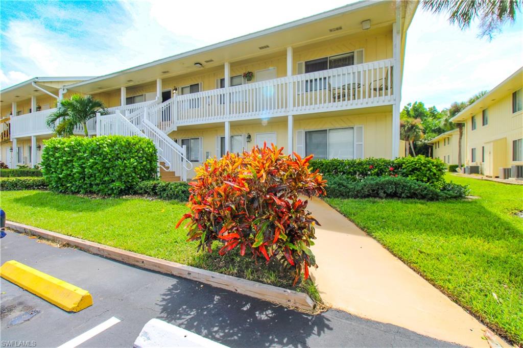 4615 Bayshore Drive, Unit E4 Naples, FL 34112 - Photo 3 of 30 a front view of a house with a yard and potted plants