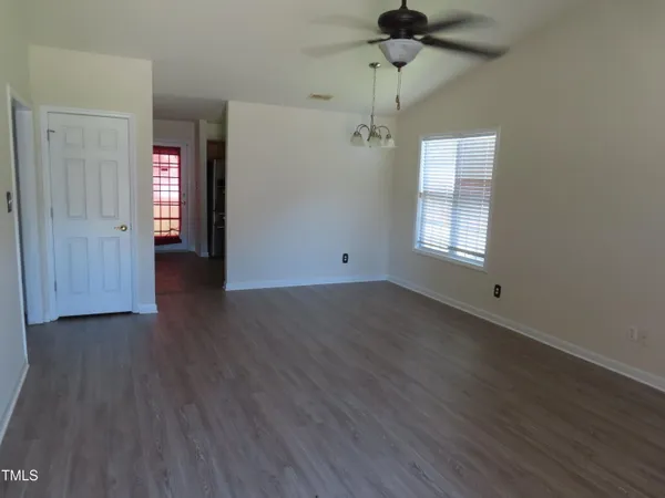 an empty room with wooden floor ceiling fan and windows