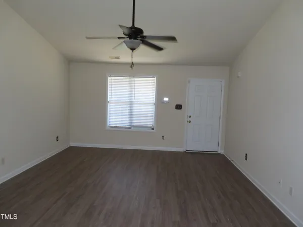 a view of an empty room with wooden floor and a window