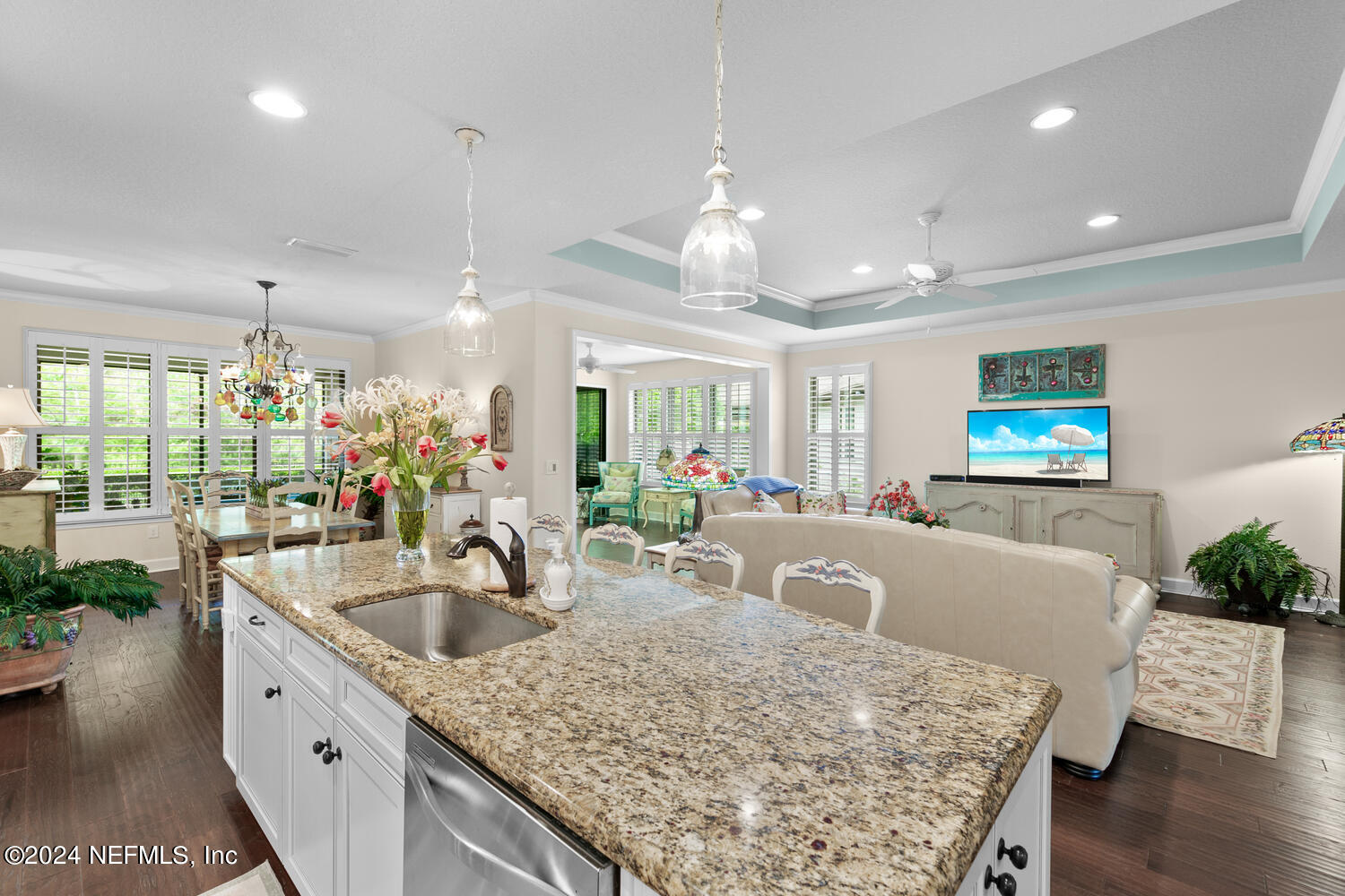 a kitchen with stainless steel appliances granite countertop a sink dishwasher and a flat screen tv