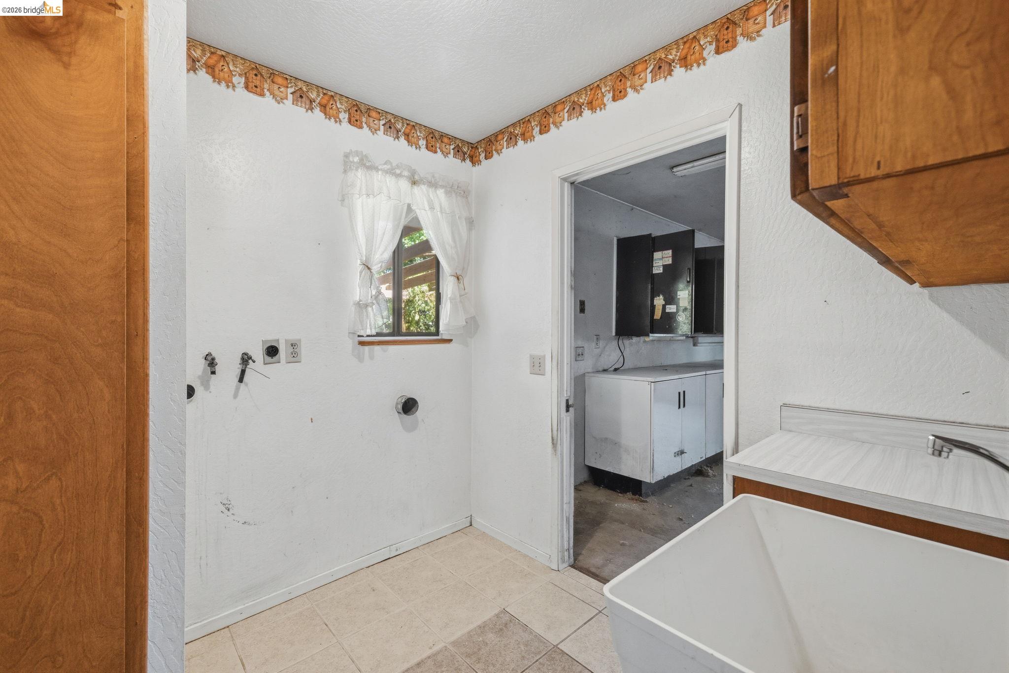 22401 South Fork Road Sonora, CA 95370 - Photo 18 of 34 Utility room featuring a window, tile flooring, and a utility sink with an adjacent wood-finish cabinet