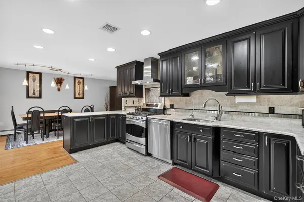 a large kitchen with stainless steel appliances wooden cabinets a stove a sink a dining table and chairs