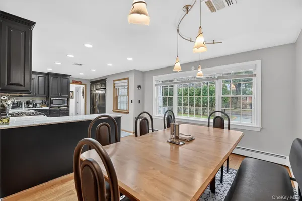 a kitchen with granite countertop a table chairs in it and wooden floors