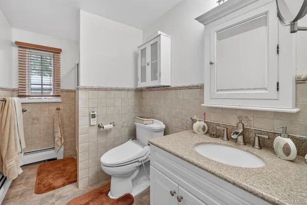 a bathroom with a granite countertop sink a toilet and a mirror