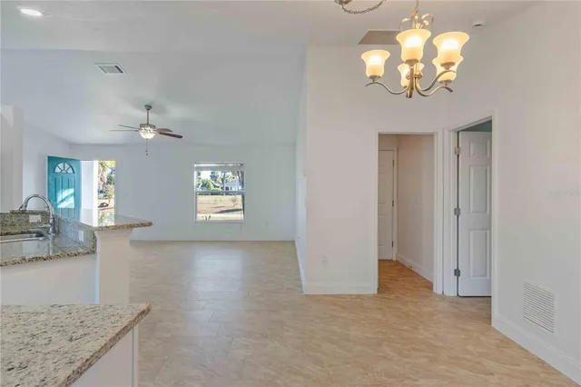 an empty room with chandelier fan and windows