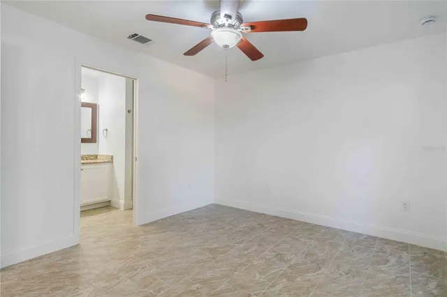 a view of an empty room and chandelier fan