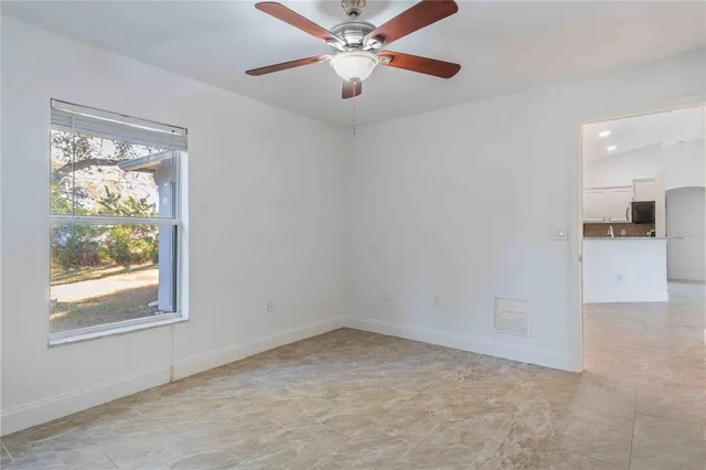 an empty room with windows and fan