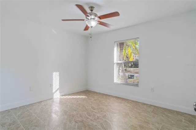 an empty room with windows and fan